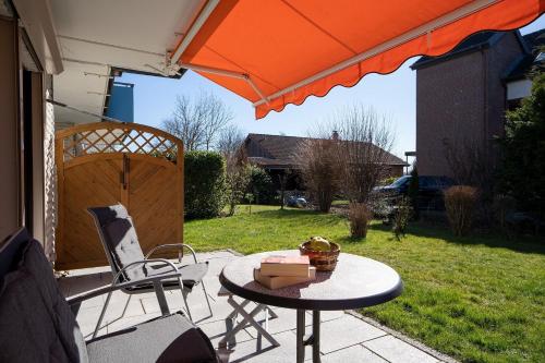 a patio with a table and chairs and an umbrella at Deichhof 3a Dünenwind in Kellenhusen