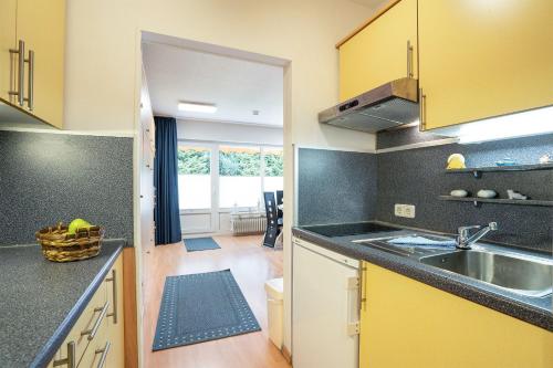 a kitchen with yellow cabinets and a sink at Deichhof 3a Dünenwind in Kellenhusen