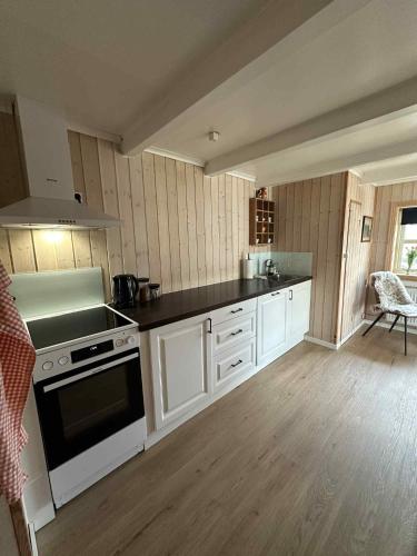 a kitchen with white cabinets and a stove top oven at Beggustova - located in Kaldbak village, close to Tórshavn in Kaldbak