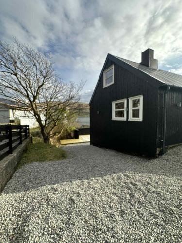 a black building sitting on top of a pile of gravel at Beggustova - located in Kaldbak village, close to Tórshavn in Kaldbak