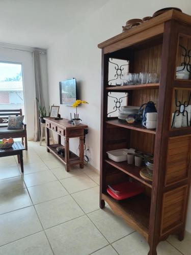 a living room with a wooden book shelf and a table at Lindo apto em frente ao Mar - Ilhéus - Itacaré Ba in Ilhéus