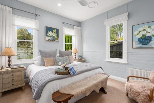 una camera con un grande letto e due finestre di Cherry Cottage Bowral a Bowral