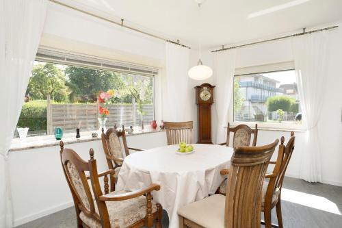 une salle à manger avec une table, des chaises et une horloge dans l'établissement Ferienhaus Nachtmann, à Kellenhusen