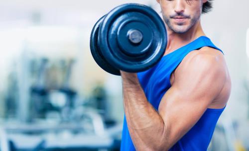 a man lifting a dumbbell in a gym at Metropolitan Al Mafraq Hotel in Abu Dhabi