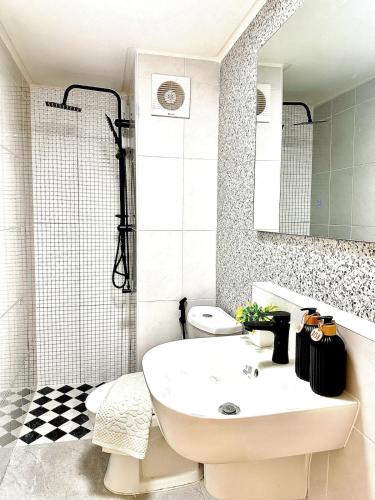 a white bathroom with a sink and a shower at CinCin Popular Condo in Thung Si Kan