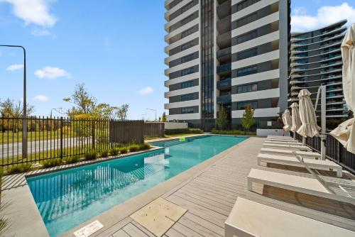 a swimming pool with umbrellas next to a building at Stylish 2-Bed Apartment with Luxe Amenities Access in Phillip