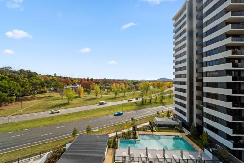 an apartment building with a swimming pool next to a road at Stylish 2-Bed Apartment with Luxe Amenities Access in Phillip