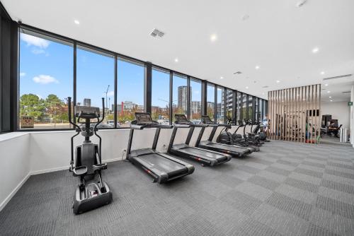 a row of exercise bikes in a gym with windows at Stylish 2-Bed Apartment with Luxe Amenities Access in Phillip