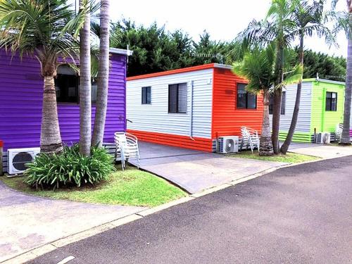 a row of mobile homes with palm trees and a street at Sussex Palms Holiday Park in Sussex inlet