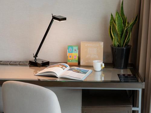 a desk with a book and a lamp and a book at Olive Tree Hotel Penang in Bayan Lepas