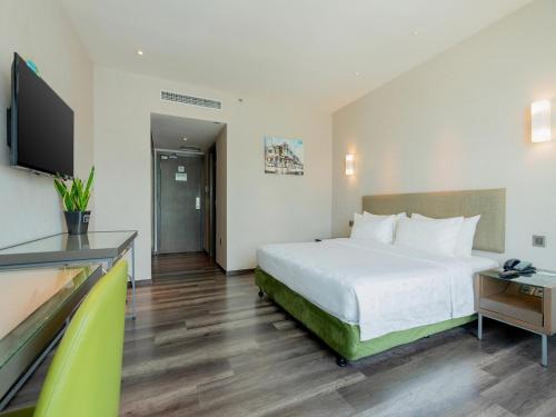 a hotel room with a bed and a flat screen tv at Olive Tree Hotel Penang in Bayan Lepas