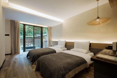 a hotel room with two beds and a large window at 青城山坐忘森林疗愈酒店 in Dujiangyan
