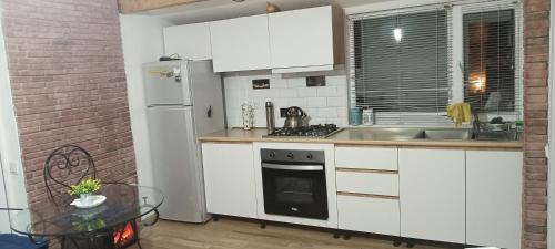 a kitchen with white appliances and a brick wall at Ksenia's apartment in Borjomi
