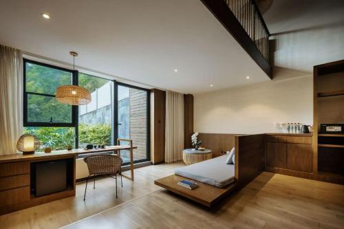 a bedroom with a bed and a desk and a table at 青城山坐忘森林疗愈酒店 in Dujiangyan