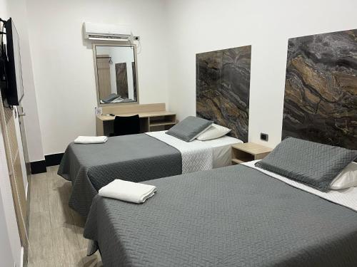 ein Hotelzimmer mit 3 Betten und einem Spiegel in der Unterkunft DUSANO BOUTIQUE HOTEL in Santa Marta