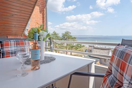 a table with a bottle and a wine glass on a balcony at Strandburg Ostseeblick Scharbeutz in Scharbeutz