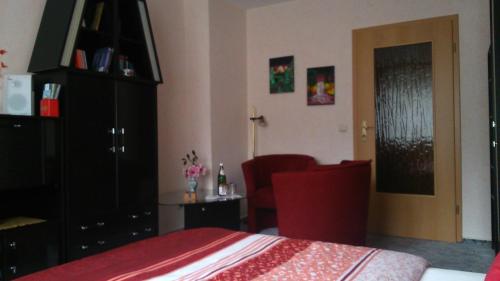 a bedroom with a red bed and a black cabinet at Ferienwohnung Anna in Greiz