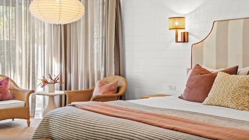 a bedroom with a bed and two chairs at Fletcher Lane Boutique Stay Byron Central in Byron Bay