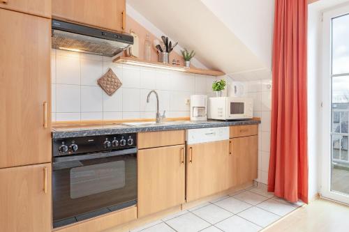 a kitchen with a stove top oven next to a window at Am Hafen 2d Inselsonne 2 in Orth