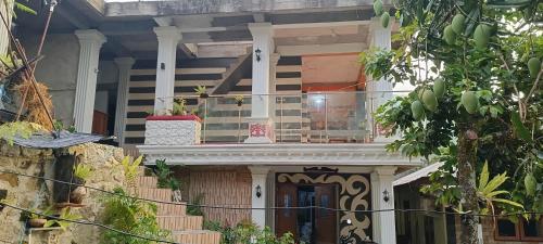 a house with a balcony on top of it at Bloom Home Stay in Tuk Tuk