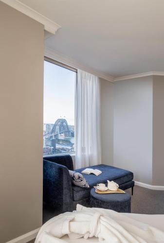 a room with a bed and a couch and a window at The Sebel Quay West Suites Sydney in Sydney
