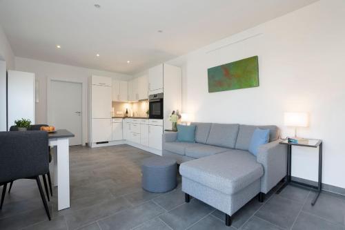 Una sala de estar con un sofá y una mesa y una cocina. en Haus Alouette, en Dahme