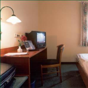 Zimmer mit einem Schreibtisch, einem Computermonitor und einem Stuhl in der Unterkunft ARC Hotel in Dieskau