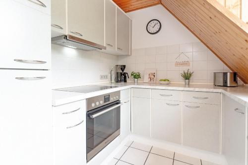 a kitchen with white cabinets and a clock on the wall at Steenkamp 32 Aus-Zeit in Timmendorfer Strand