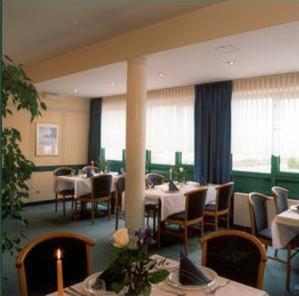 uma sala de jantar com mesas, cadeiras e janelas em ARC Hotel em Dieskau