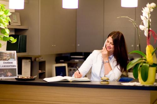 a woman sitting at a counter writing in a book at Hotel Lamberti in Alassio