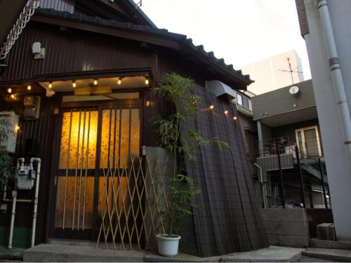a building with a door and a plant in front of it at Minkago 鹿児島駅前 #KG1 in Kagoshima