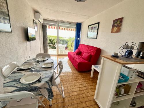 un salon avec une table et un canapé rouge dans l'établissement Studio climatisé pour 2 avec terrasse et parking près des plages - FR-1-338-613, à Sète