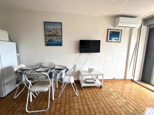 une salle à manger avec une table et des chaises et une télévision dans l'établissement Studio climatisé pour 2 avec terrasse et parking près des plages - FR-1-338-613, à Sète
