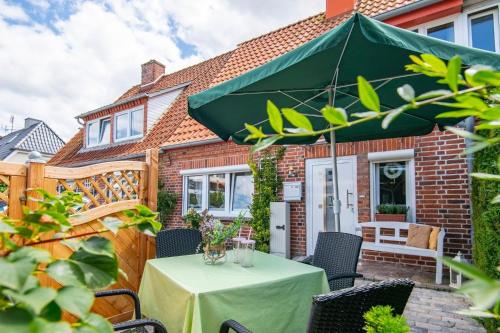 a patio with a table with a green umbrella at Heckenröschen in Grömitz