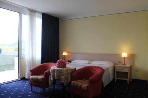 a hotel room with a bed and two chairs at Terme Villa Pace in Abano Terme