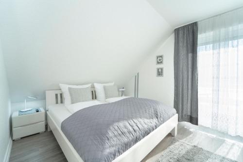 a white bedroom with a bed and a window at Blankwasserweg 16- Sonnenseite in Grömitz