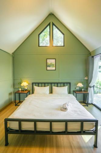 a bedroom with a large white bed with a window at Green Garden House กรีนการ์เด้นเฮ้าส์ นครพนม in Nakhon Phanom