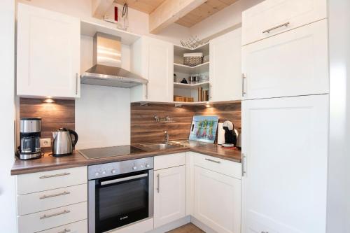 a kitchen with white cabinets and a sink at Seepark Süssau Ferienhaus Seehund 1 in Süssau