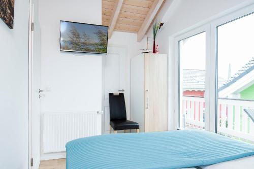 a bedroom with a blue bed and a chair at Seepark Süssau Ferienhaus Seehund 1 in Süssau