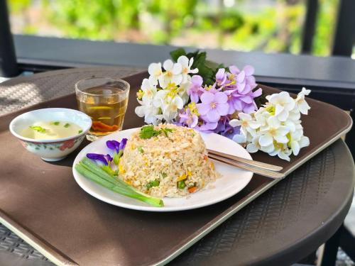 Green Garden House กรีนการ์เด้นเฮ้าส์ นครพนม في ناخون فانوم: طبق طعام مع الأرز والزهور على صينية