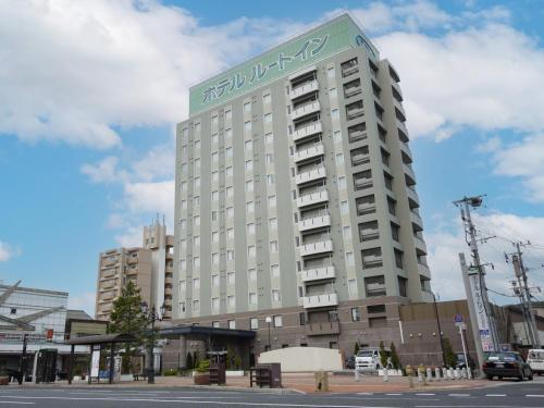 a tall white building with a sign on it at Hotel Route-Inn Kitakyushu-Wakamatsu Ekihigashi in Kitakyushu