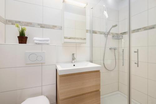 a white bathroom with a sink and a shower at Lütt Drosselhörn 2 in Laboe