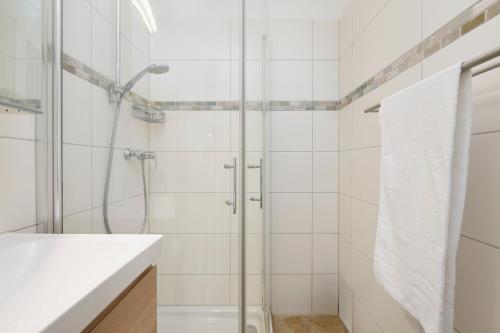 a white bathroom with a shower and a sink at Lütt Drosselhörn 2 in Laboe