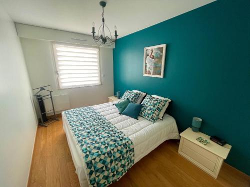 une chambre avec un lit avec un mur bleu dans l'établissement T2 Lumineux Face Mer avec Terrasse et Garage - Quartier des Présidents, Proche Plage et Commerces - FR-1-92-900, à Les Sables-dʼOlonne