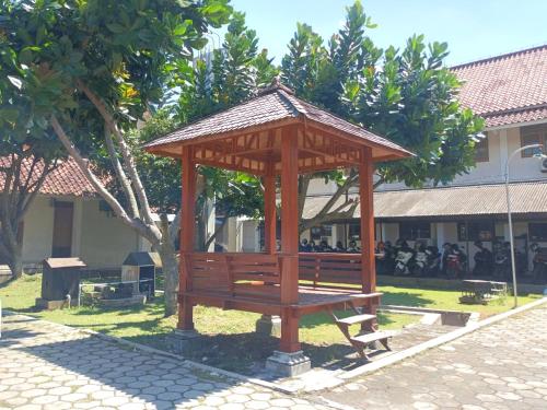 a wooden gazebo with a bench in a park at Wisma Colomadu in Tjolomadu