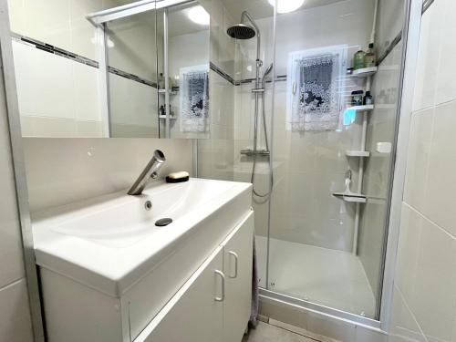 une salle de bain blanche avec un lavabo et une douche dans l'établissement Saint-Cyprien - Duplex 2 chambres avec terrasse et parking privé, vue sur le port - FR-1-309-507, à Saint-Cyprien