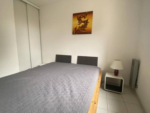 une chambre avec un lit et une table avec une lampe dans l'établissement Appartement 3 Pièces Moderne avec Loggia, 6 Personnes, Proche Plage - FR-1-750-82, à Canet
