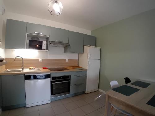 une cuisine avec des armoires vertes et un réfrigérateur blanc dans l'établissement Appartement charmant proche plage avec terrasse et parking - FR-1-239-1119, à Labenne