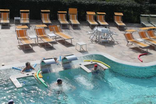 a swimming pool with chairs and people playing in it at Terme Villa Pace in Abano Terme
