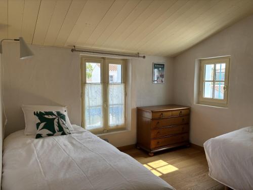 a bedroom with two beds and a dresser and a window at Maison noirmoutrine confortable pour 7 pers avec jardin et parking - FR-1-823-152 in Noirmoutier-en-l'lle